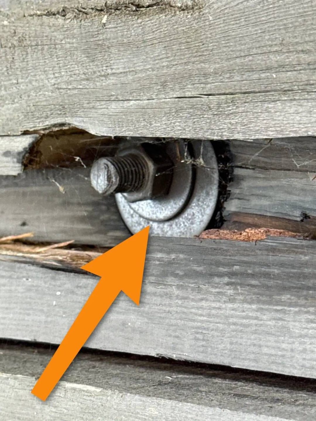 Corroded bolt and nut assembly with improperly seated washer between weathered wood framing members during a home inspection near Whitefish, MT